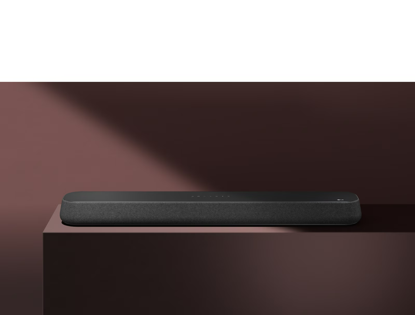 The LG Soundbar  SE6S is placed on the red box in front of red background. A black shadow is covering the upper right half of the picture.
